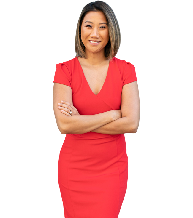 A person in a red dress stands with arms crossed, smiling at the camera.